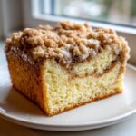 Close-up of a thick slice of moist coffee cake featuring a rich cinnamon swirl and generous streusel crumb topping.