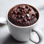 Close-up of a freshly baked chocolate mug cake topped with melted chocolate chips.