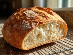 A freshly baked loaf of Italian bread, cut open to show the airy interior, resting on a cooling rack.