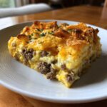 A hearty slice of Dorito Casserole featuring layers of ground sausage, eggs, melted cheese, and crunchy Doritos on top.
