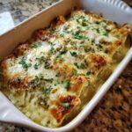 Close-up of baked green chile chicken enchiladas covered in melted, slightly browned cheese and fresh cilantro.