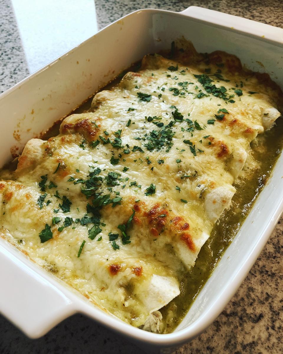 Close-up of baked green chile chicken enchiladas covered in melted, bubbly cheese and fresh cilantro.