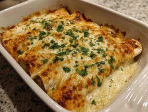 Close-up of baked green chile chicken enchiladas covered in bubbly, melted cheese and fresh parsley.