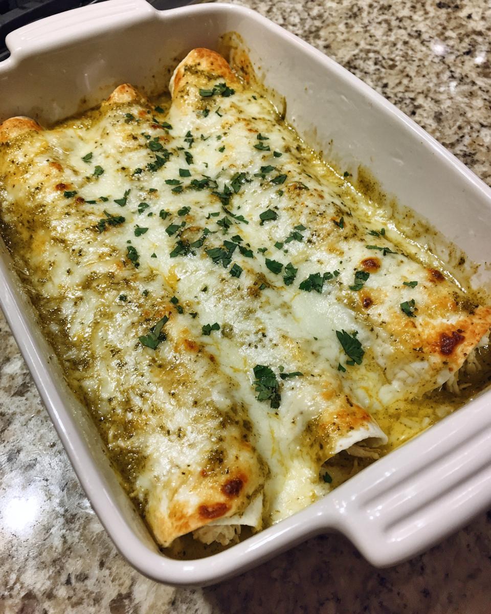 Close-up of baked green chile chicken enchiladas covered in melted white cheese and sprinkled with fresh cilantro.