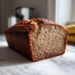 Close-up of a moist sugar free banana bread loaf showing its crumb texture on a marble surface.