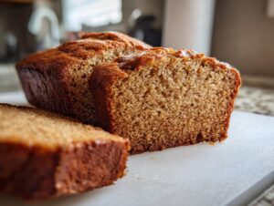 Close-up of a moist sugar free banana bread loaf, with one thick slice cut and resting in front.