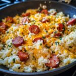 Close-up of a one-pot sausage and rice dish topped with shredded cheddar cheese and fresh parsley.