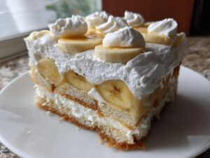 A generous slice of amazing banana pudding featuring layers of cake, creamy filling, sliced bananas, and topped with whipped cream dollops.