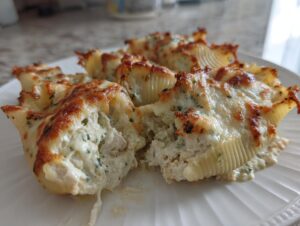Close-up of baked chicken alfredo stuffed shells, showing the creamy filling and browned, cheesy topping.