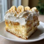 A generous slice of creamy banana pudding layered with vanilla wafers, topped with whipped cream, banana slices, and crumbs.