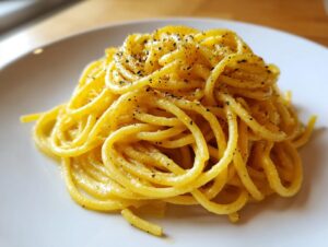 A close-up shot of a perfectly twirled serving of creamy lemon pasta topped generously with freshly cracked black pepper.