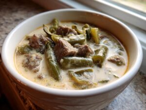 Close-up of a hearty bowl of philly cheese steak soup featuring chunks of beef and green peppers in a creamy, cheesy broth.
