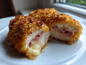Cross-section of a perfectly cooked chicken cordon bleu showing melted cheese and ham filling.
