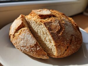 A rustic, round loaf of freshly baked soda bread, cut open to show the soft interior crumb.