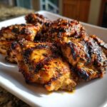 Close-up of perfectly grilled chicken thighs coated in herbs, showing char marks from the grill, made with the best chicken marinade.