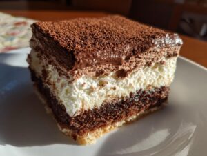 Close-up of a square slice of italian love cake showing three distinct layers: cake base, white cream, and chocolate mousse topped with cocoa powder.