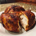 Close-up of a perfectly roasted spatchcock chicken, cut open to show the moist, white breast meat inside the crispy skin.