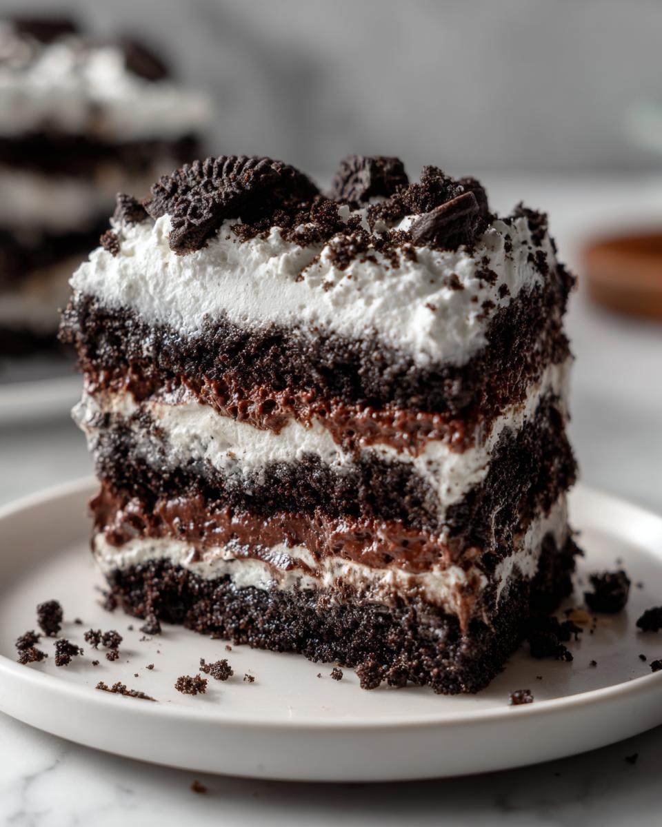 Close-up of a layered slice of amazing dirt cake featuring dark chocolate cake, creamy filling, and whipped topping.