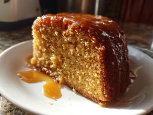 Close-up of a moist slice of Bacardi Rum Cake topped with a thick, shiny rum glaze dripping down the side.