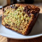 Close-up of a moist slice of banana zucchini bread with visible shredded zucchini and melted chocolate chips.