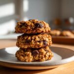 A stack of three hearty oatmeal chocolate chip breakfast cookie on a light plate.