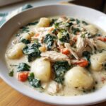 A close-up of a creamy bowl of Olive Garden Chicken Gnocchi Soup, featuring shredded chicken, spinach, carrots, and soft gnocchi.