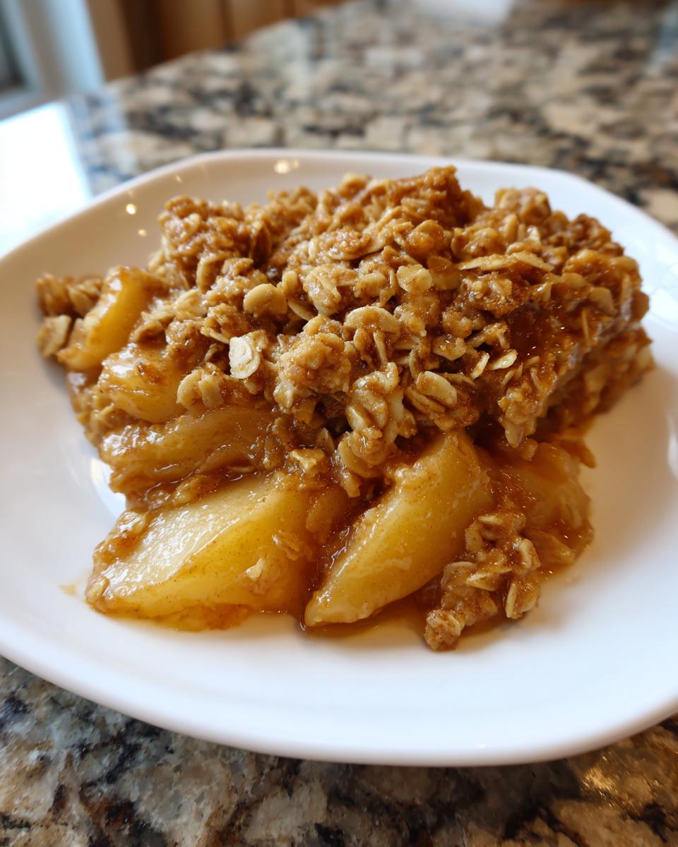 A close-up of a warm serving of pear crisp with a thick, crunchy oat topping.