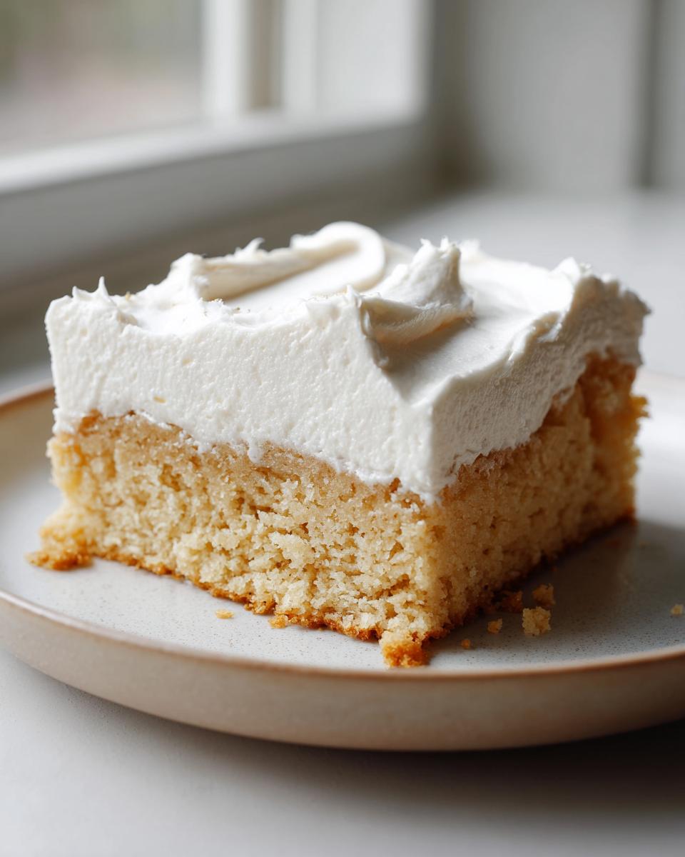A thick slice of golden sugar cookie bars topped with a generous layer of white frosting.