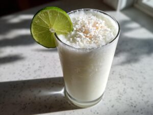 A frosty white Christmas margarita garnished with shredded coconut and a fresh lime wheel.