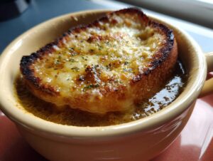 Close-up of a crockpot french onion soup slow cooker serving with melted, browned cheese on a crouton.