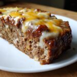 Close-up of a moist slice of crockpot french onion soup meatloaf with melted Swiss cheese topping.