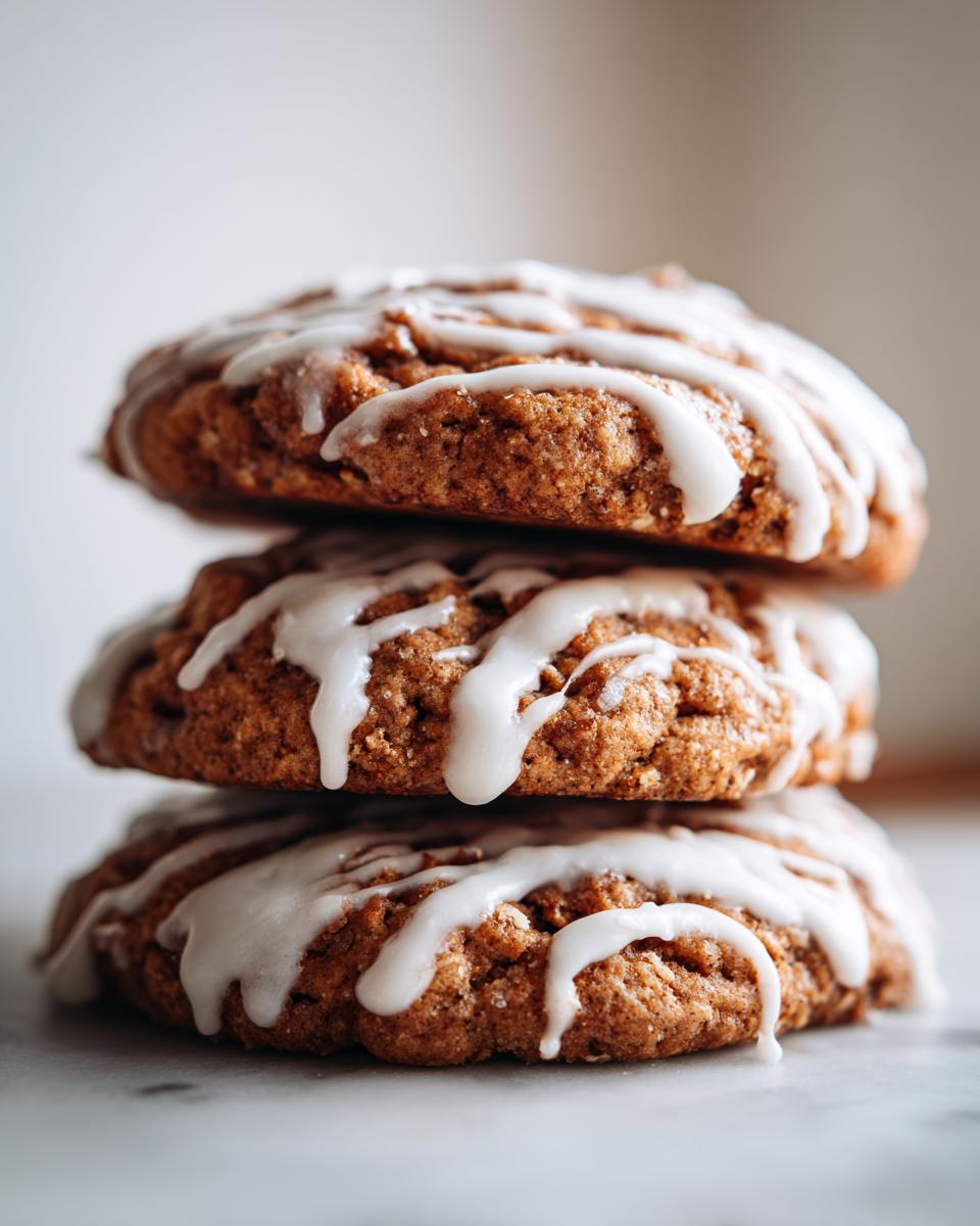 Three stacked, round gluten free sourdough discard cinnamon rolls topped with white glaze.