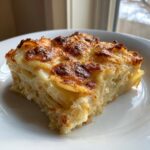 A close-up of a rich, layered slice of potatoes au gratin with a perfectly browned and bubbly cheese crust.