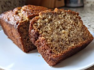 Close-up of two slices of rich, moist flourless peanut butter banana bread on a white plate.